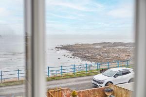 a window view of a car parked next to the ocean at Host & Stay - Twelve On The Terrace in Newbiggin-by-the-Sea