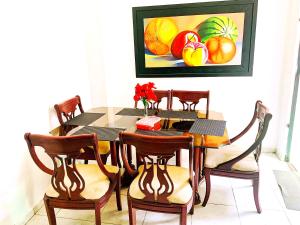 a dining room table with chairs and a painting of fruit at Golden House festivalera II para 10 personas in Valledupar +8 photos