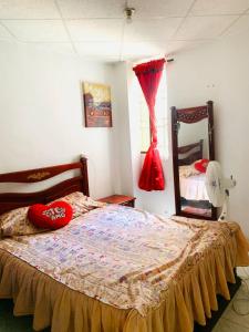 a bedroom with a bed with red pillows and a window at Golden House festivalera II para 10 personas in Valledupar