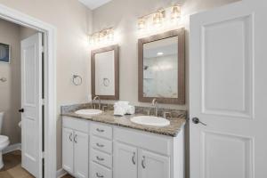 a bathroom with two sinks and two mirrors at Beach Baby by Gulf Coast Getaways in Navarre