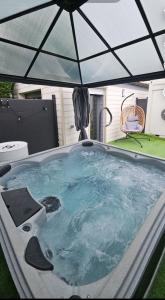 a hot tub with an umbrella in a yard at hébergement privée Jaccuzzi en supplément in Saint-Clair-du-Rhône