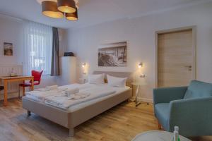 a bedroom with a bed and a couch and a chair at Zur Eiche in Ahlbeck