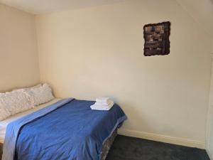 a bedroom with a bed with blue sheets and a wall at Realwood Homes- Birrell Road in Nottingham
