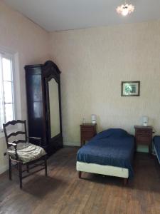 una camera da letto con un letto, una sedia e uno specchio di Arcachonaise à 50 m de la plage, Arcachon Centre ad Arcachon