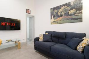 a living room with a blue couch and a painting at Elegantis Trastevere Modern Apartment - Comfort in Rome Most Charming District in Rome