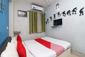 a bedroom with a bed with red pillows and a tv at Hotel O Sher E Bengal in Durgāpur