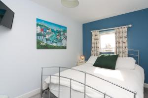 a bedroom with a white bed and a blue wall at Cosy seaside cottage in Criccieth