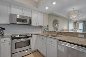 a kitchen with white cabinets and stainless steel appliances at Bikini Bottom by Gulf Coast Getaways in Navarre