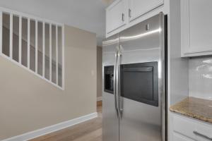 a stainless steel refrigerator in a kitchen with white cabinets at Bikini Bottom by Gulf Coast Getaways in Navarre