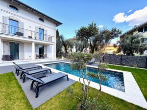 een huis met een zwembad en twee banken bij Villa Sembenini Loft in Riva del Garda