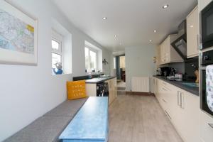 a kitchen with white cabinets and a blue counter top at 6 Afallon, Beachside holiday house in Criccieth