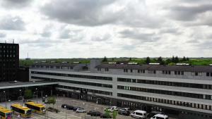 a large white building with cars parked in a parking lot at The Break Hotel in Herning