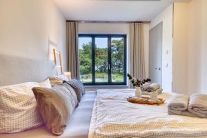 een slaapkamer met een bed en een groot raam bij Ferienwohnung Ostseeloft 5 im Haus Prora Düne 7 in Binz