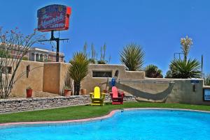 a swimming pool with two colorful chairs next to a house at The Maverick Inn in Alpine
