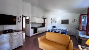 a living room with a yellow couch and a kitchen at CASA PISCINA Fois in San Teodoro