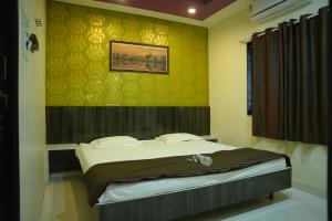 Un dormitorio con una cama y un cuadro en la pared. en New Palange Bhakt Niwas, en Tuljapur