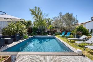 einen Pool im Hinterhof mit Stühlen und einem Sonnenschirm in der Unterkunft 339 - La Balinaise - Villa with pool in Sainte-Marie-de-Ré