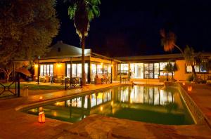 a swimming pool in front of a house at night at Auob Country Lodge in Gochas