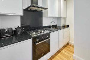 a kitchen with white cabinets and a stove top oven at Host & Stay - Eton House in Eton +6 photos