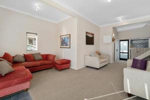 マウント・マウンガヌイにあるHome Sweet Home - Mt Maunganui Holiday Homeのリビングルーム(赤いソファ、椅子付)