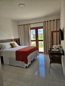 a bedroom with a bed and a desk and a window at Apartamentos Recanto do Rouxinol em Serra de São Bento RN in Serra de São Bento