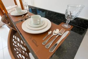a wooden table with plates and silverware on it at Apartamentos Recanto do Rouxinol em Serra de São Bento RN in Serra de São Bento