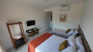 a hotel room with a bed and a television at Apartamentos Recanto do Rouxinol em Serra de São Bento RN in Serra de São Bento