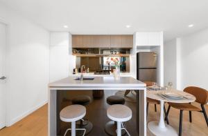 una cocina con una gran isla blanca con taburetes en The Oracles Tower - Lv 31 Dreamy Stay Above The Star Casino, en Brisbane