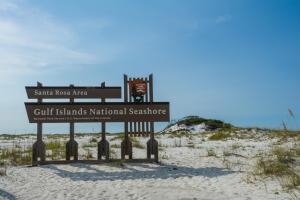 ein Schild im Sand am Strand in der Unterkunft Once Upon A Tide by Gulf Coast Getaways in Navarre