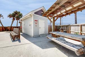 a building with two benches and a picnic table at Tiki House in Corpus Christi