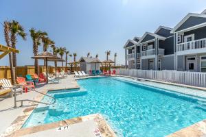 a swimming pool with chairs and palm trees at Tiki House in Corpus Christi