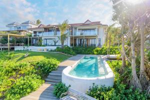 a villa with a swimming pool and a house at Sala Beach House in Ballito