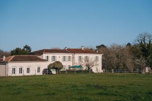 a large white house with a field in front of it at Logis de Vallombronze in Clérac