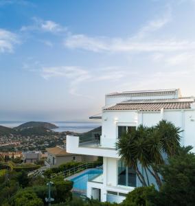a white building with a swimming pool and the ocean at Sea View Residence Panorama Villa in Saronida
