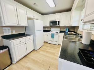 a kitchen with white cabinets and black counter tops at Eastgate 17A beautiful townhouse in Hammond
