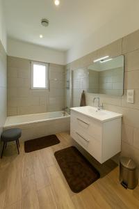a bathroom with a sink and a tub and a mirror at Jolie villa avec piscine in Monticello