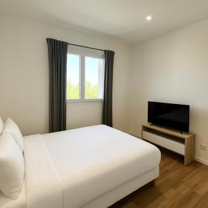 a bedroom with a white bed and a flat screen tv at Jolie villa avec piscine in Monticello