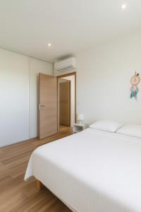 a white bedroom with a white bed and a door at Jolie villa avec piscine in Monticello +1 photo