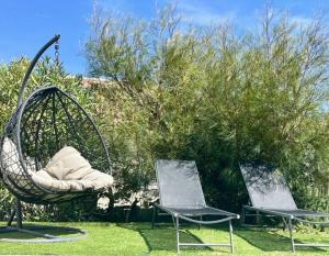 two chairs sitting in the grass next to some bushes at Jolie villa avec piscine in Monticello