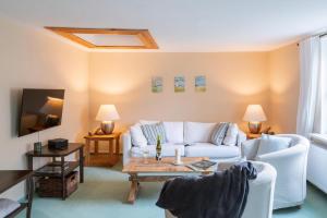 a living room with a white couch and a table at Ostseeurlaub mit Parkblick und Sauna in Rabenholz
