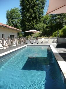 - une piscine d'eau bleue avec un parasol dans l'établissement Le Vinois, à Caillac