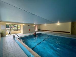 a large swimming pool with a person standing in it at 2 Bed Apartment with Shared Pool in Kingsbridge