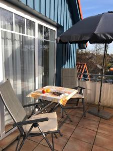 einen Tisch und Stühle auf einem Balkon mit Sonnenschirm in der Unterkunft Friedensstraße 43 Wohnung 7 in Zingst + 5 Fotos