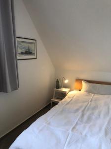 ein Schlafzimmer mit einem großen weißen Bett mit einer Lampe in der Unterkunft Friedensstraße 43 Wohnung 7 in Zingst