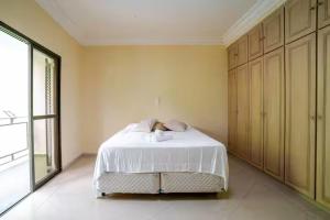 a bedroom with a white bed and a large window at Suíte privativa 5 minutos metrô com Piscina e churrasqueira in Sao Paulo