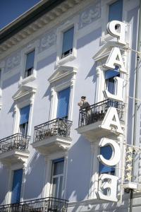 a man standing on a balcony in front of a building at Palace Hotel in Viareggio
