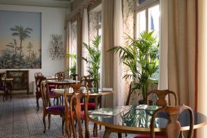 a dining room with tables and chairs and plants at Palace Hotel in Viareggio