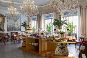 a dining room with chandeliers and tables and chairs at Palace Hotel in Viareggio