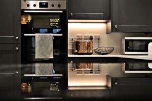 a kitchen with black cabinets and silver appliances at Upper Townhouse, Exeter in Alphington