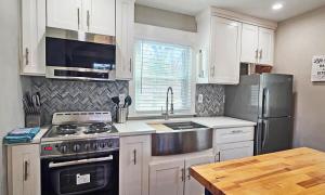 a kitchen with white cabinets and a stainless steel refrigerator at Private Atlanta Tiny House with Mini Golf in Forest Park